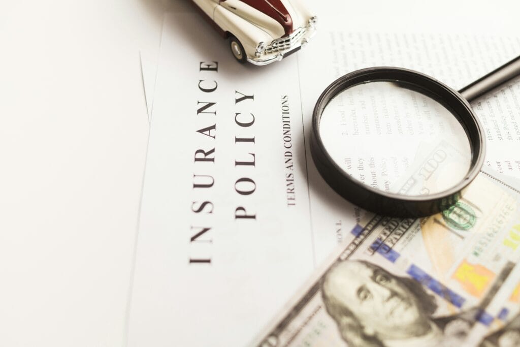 Insurance policy document with a magnifying glass, toy car, and money